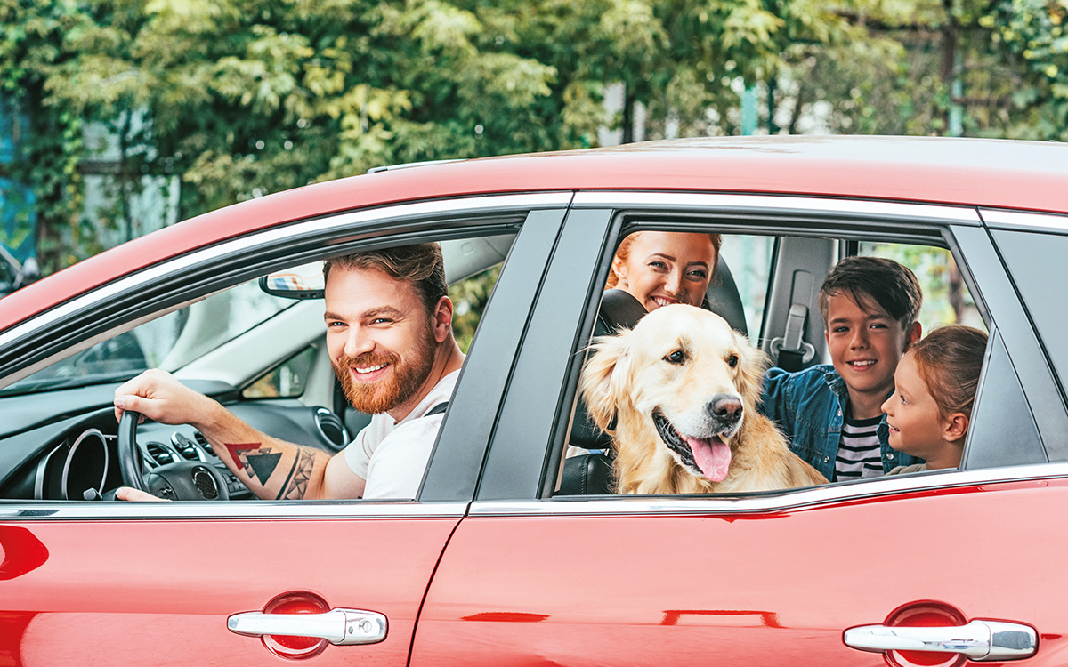 Una famiglia in macchina con il loro amico a quattro zampe: pronti alla partenza perle vacanze.